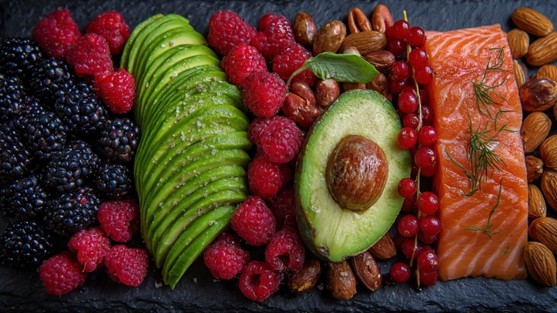 Sveže bobičasto voće, avokado, orašasti plodovi i losos složeni na tamnom tanjiru