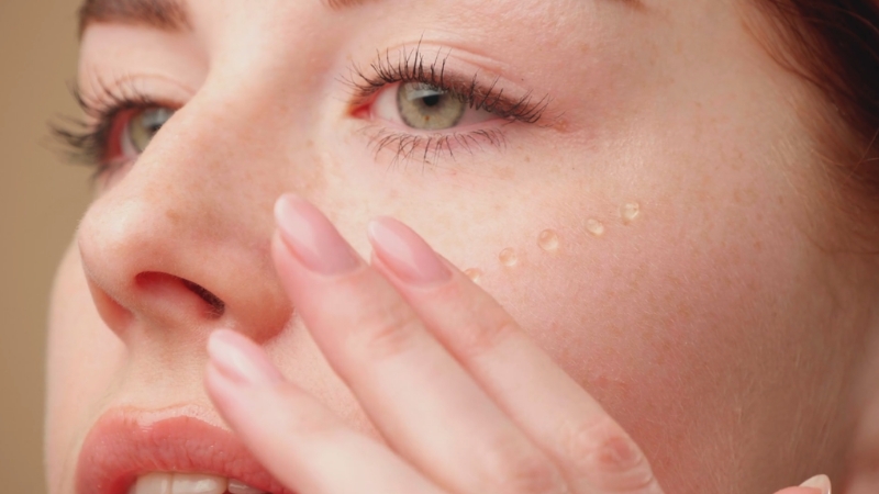 Žena sa vidljivim kapljicama retinola na obrazu