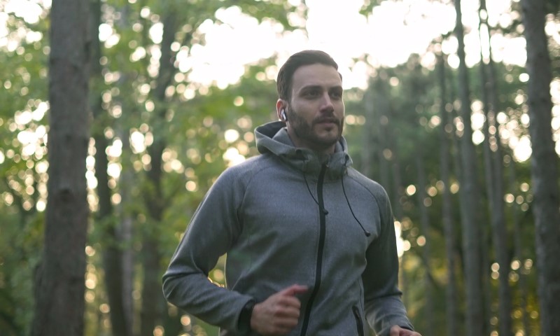 Muškarac trči kroz šumu sa slušalicama u ušima